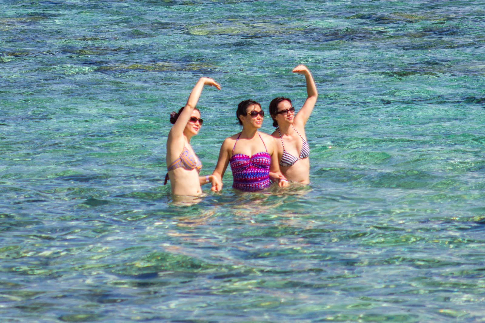 Three Asian women swimming in Tumon Bay, Guam